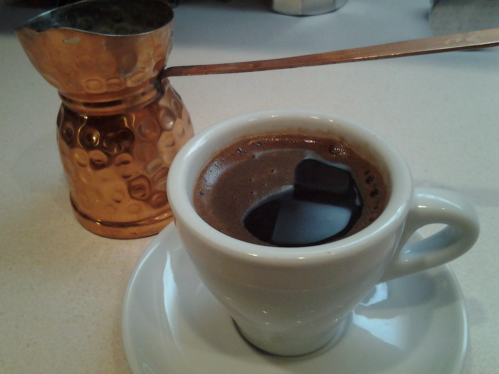 Cezve de cobre junto a una taza de café turco recién preparado